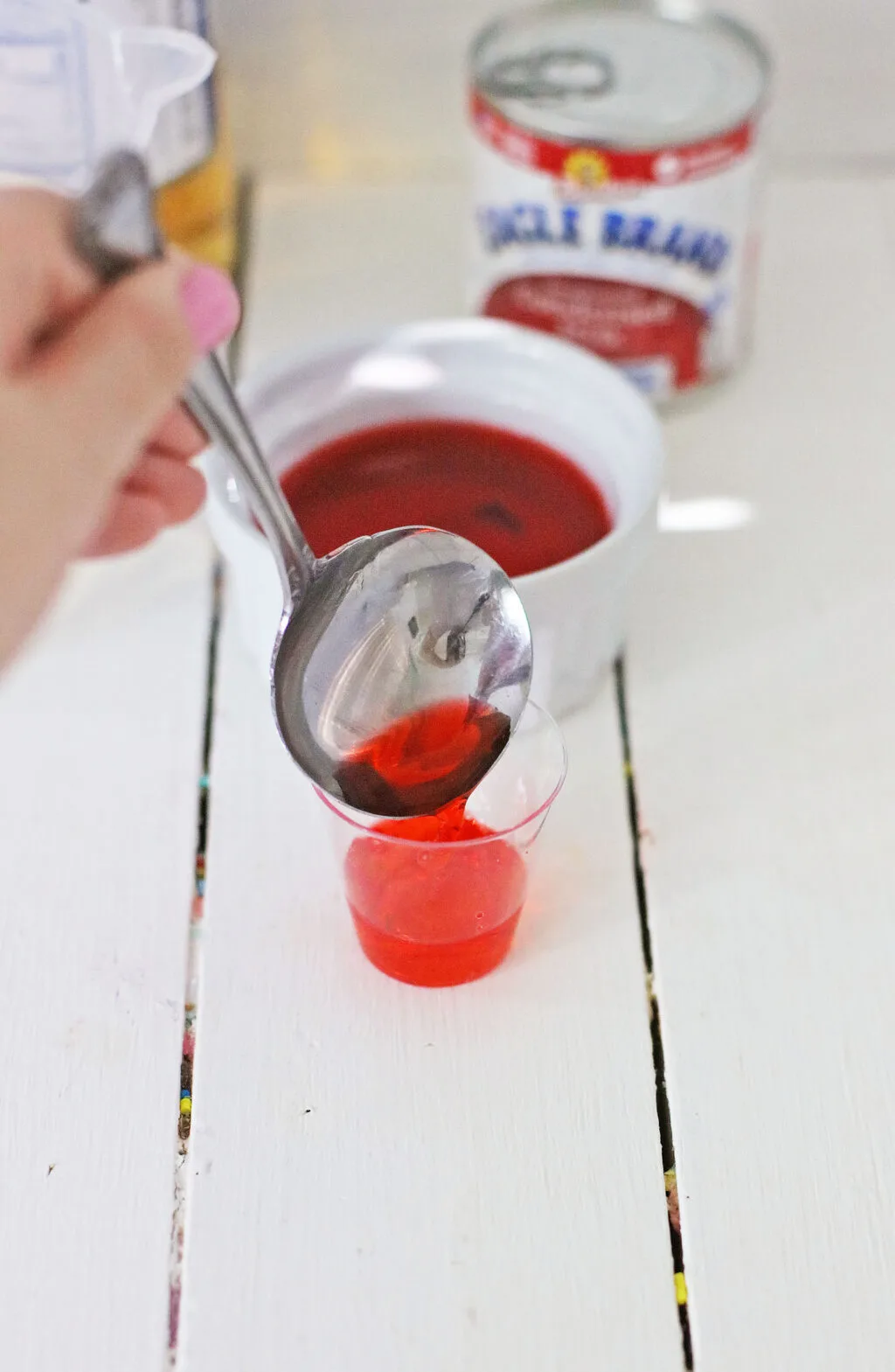 red jello being poured into jello shot glass