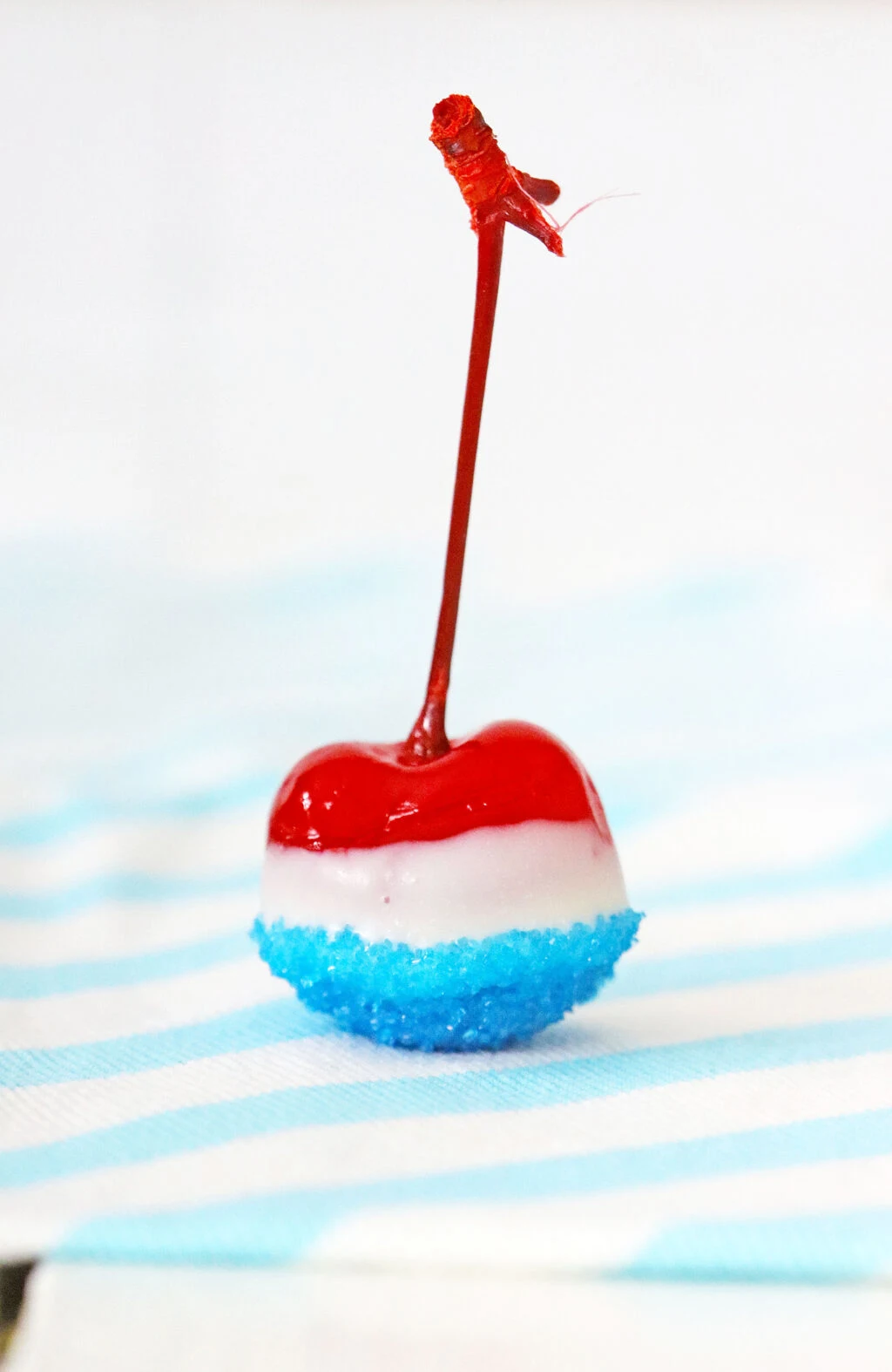 single boozy patriotic cherry bomb on a blue and white striped napkin