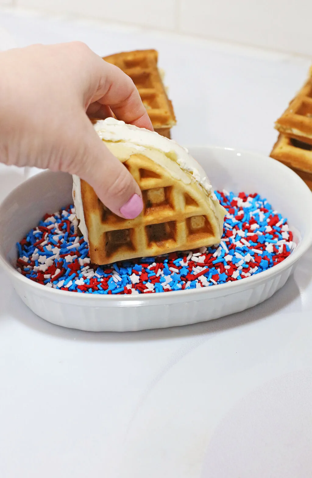 dipping edges of ice cream sandwich into sprinkles