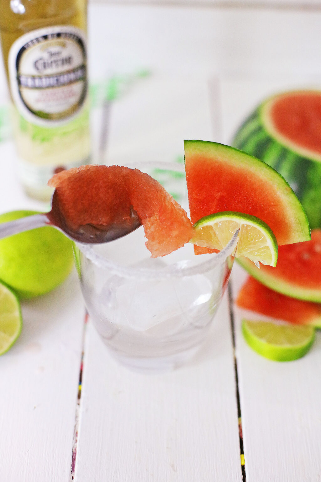 spoon putting watermelon pieces into a margarita glass