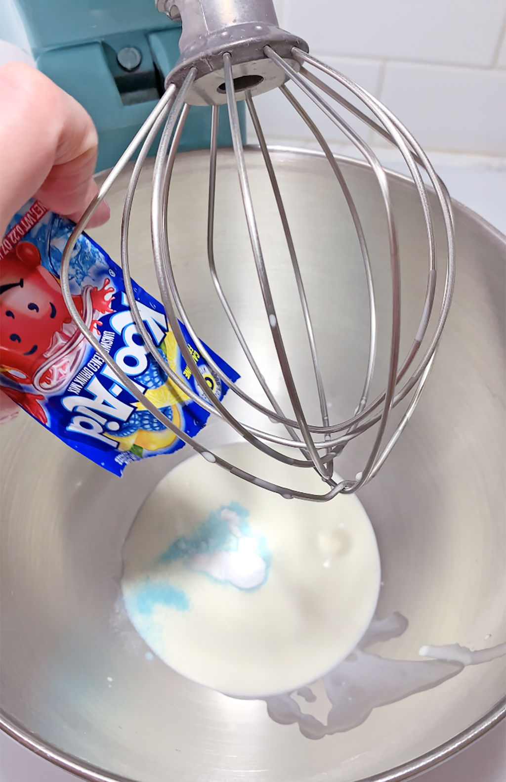 kool-aid packet being poured into large mixing bowl