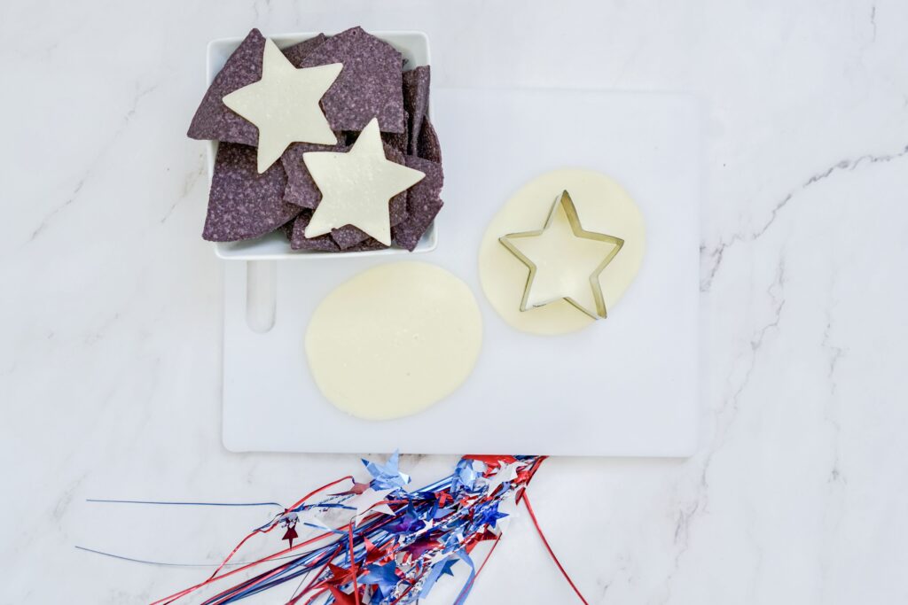 star cookie cutter cutting out pieces of white cheese into star shapes
