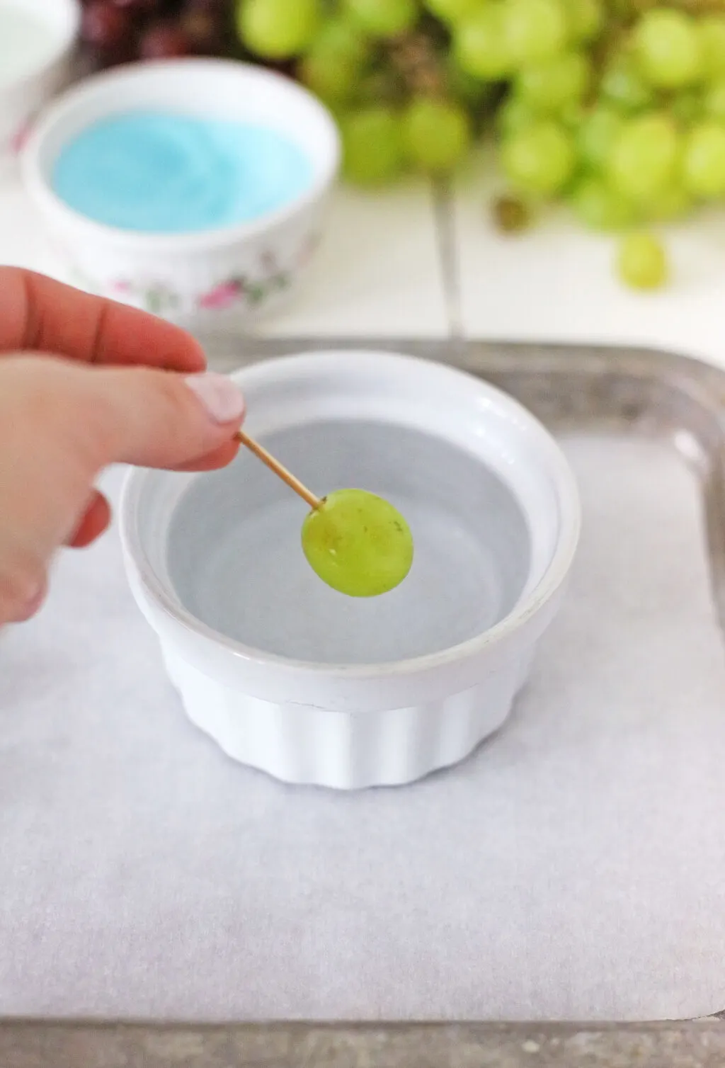 hand dipping grape into cup of water