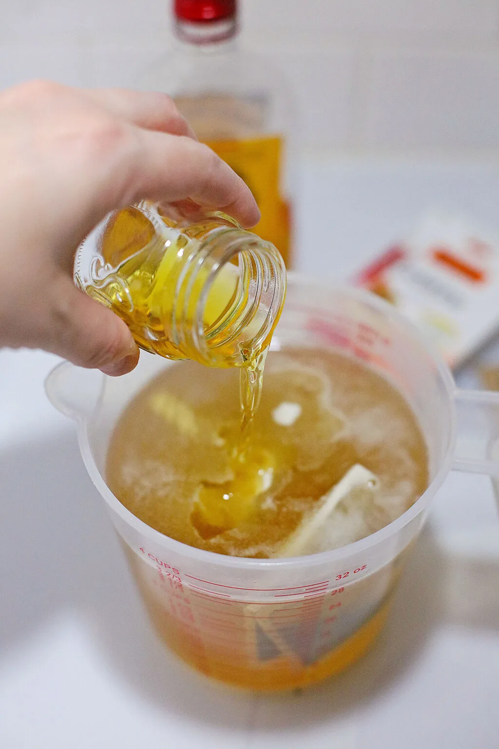 woman's hand adding whiskey to jello shot mixture