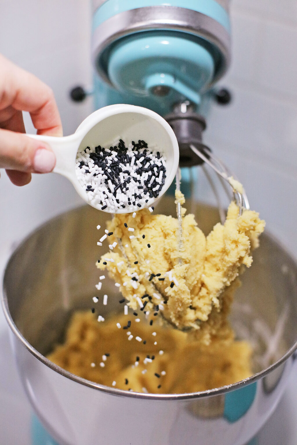 hand adding halloween sprinkles to cookie dough