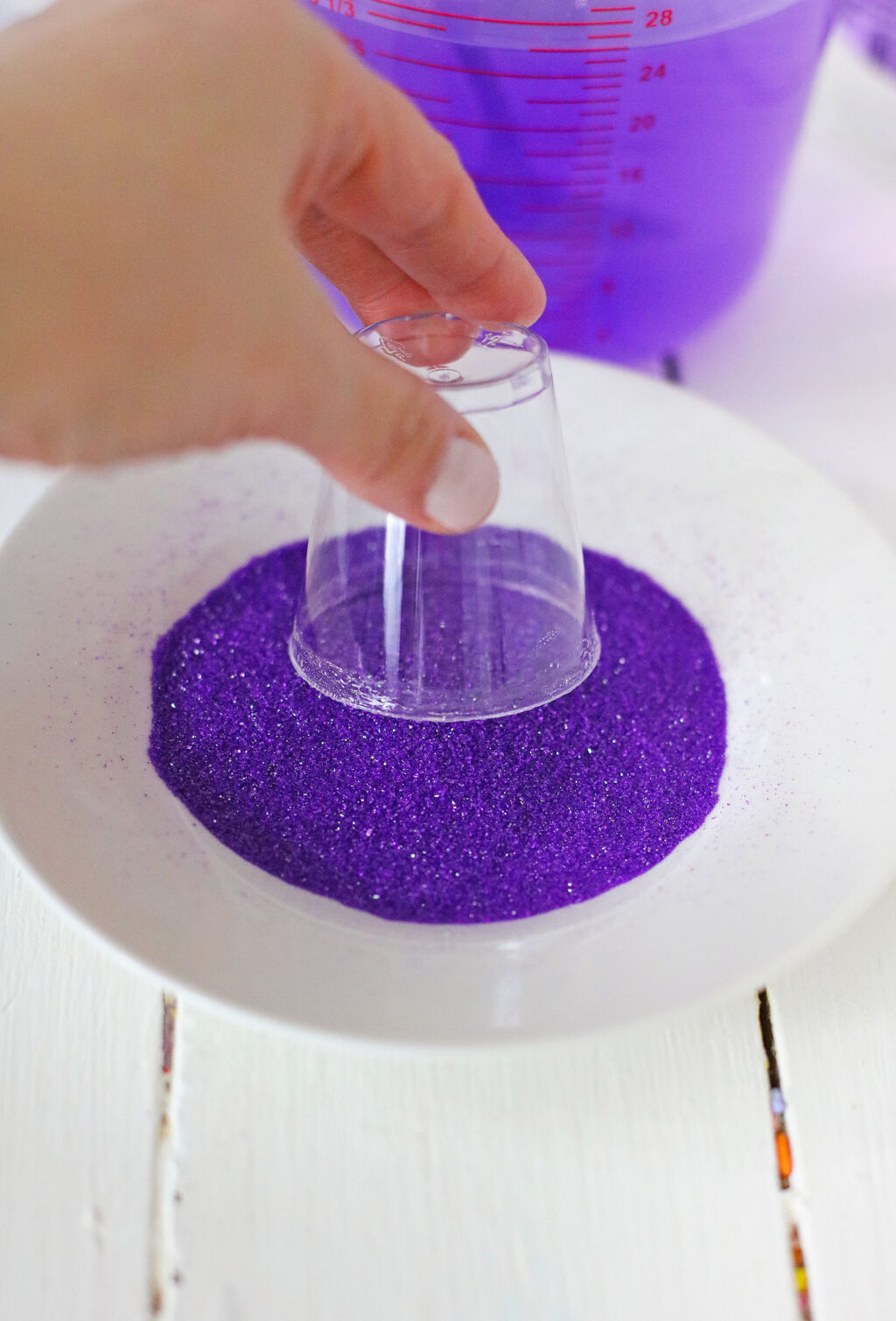 shot glass being dipped into purple sanding sugar