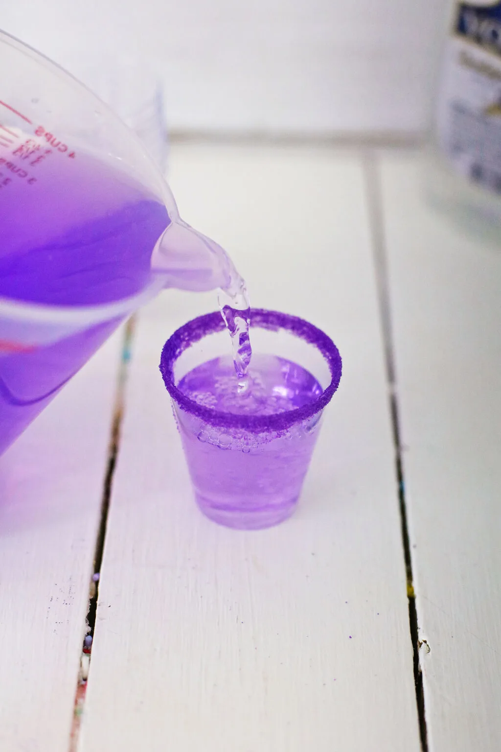 shot glass being filled with purple jello mixture
