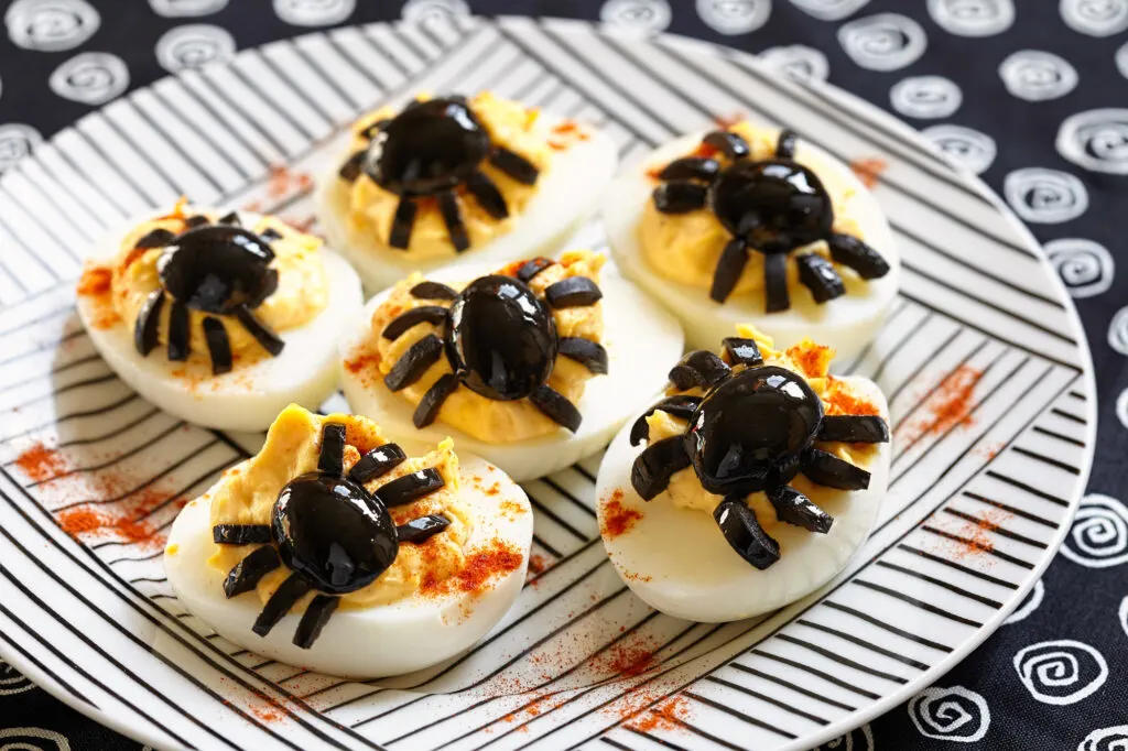 Deviled eggs with a Spider for Halloween on striped black and white plate