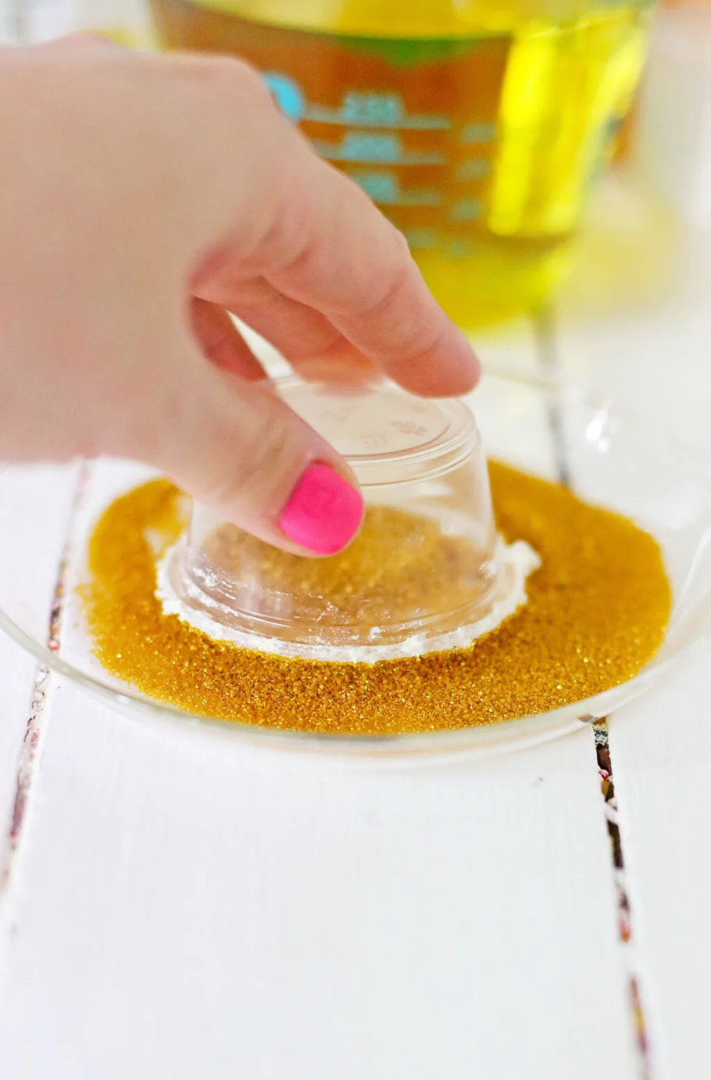 hand dipping jello shot cups into gold sprinkles