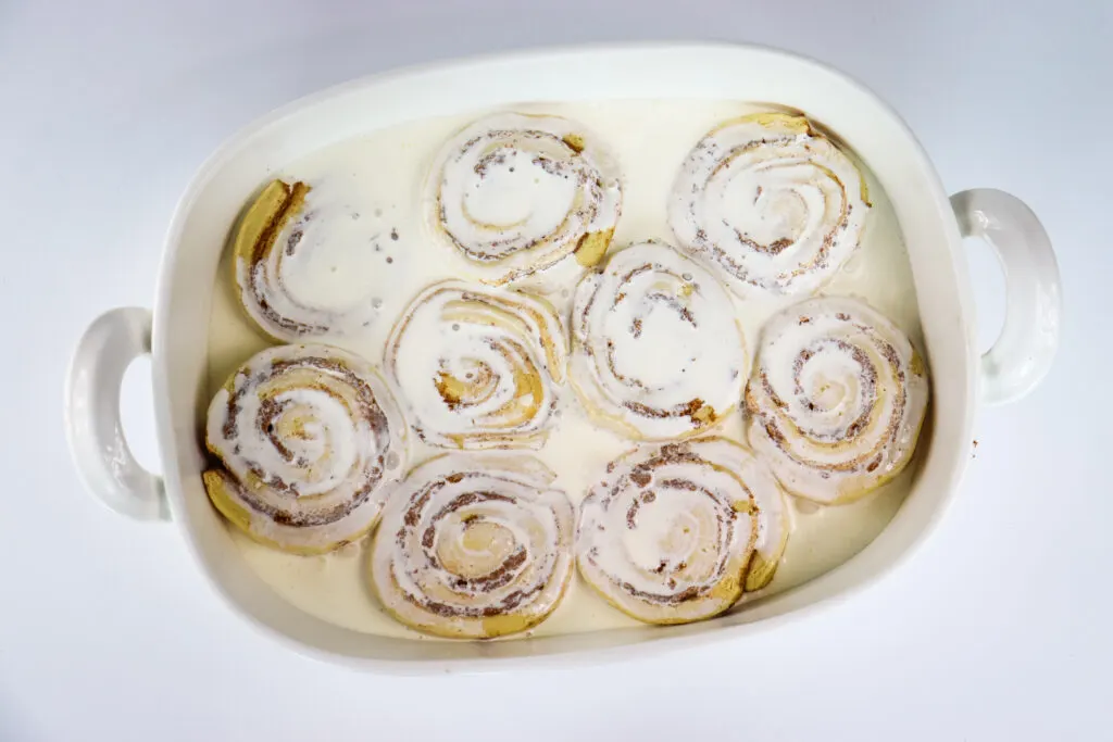heavy whipping cream poured over cinnamon rolls in baking dish