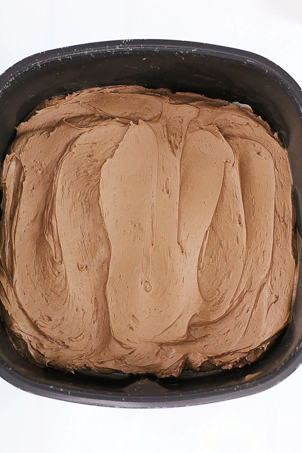 chocolate frosting covering baked brownies