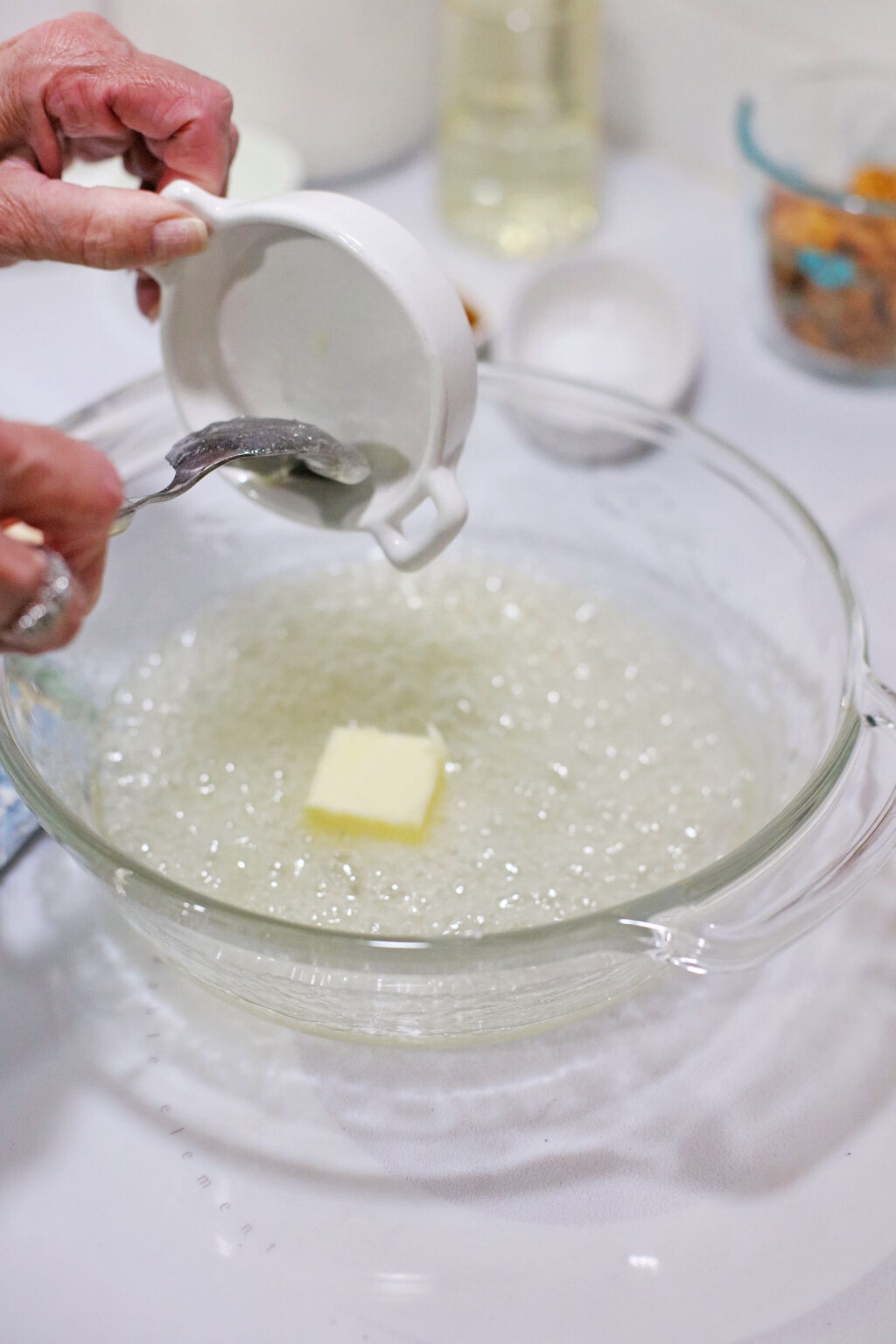 hand adding butter into hot bowl of melted sugar