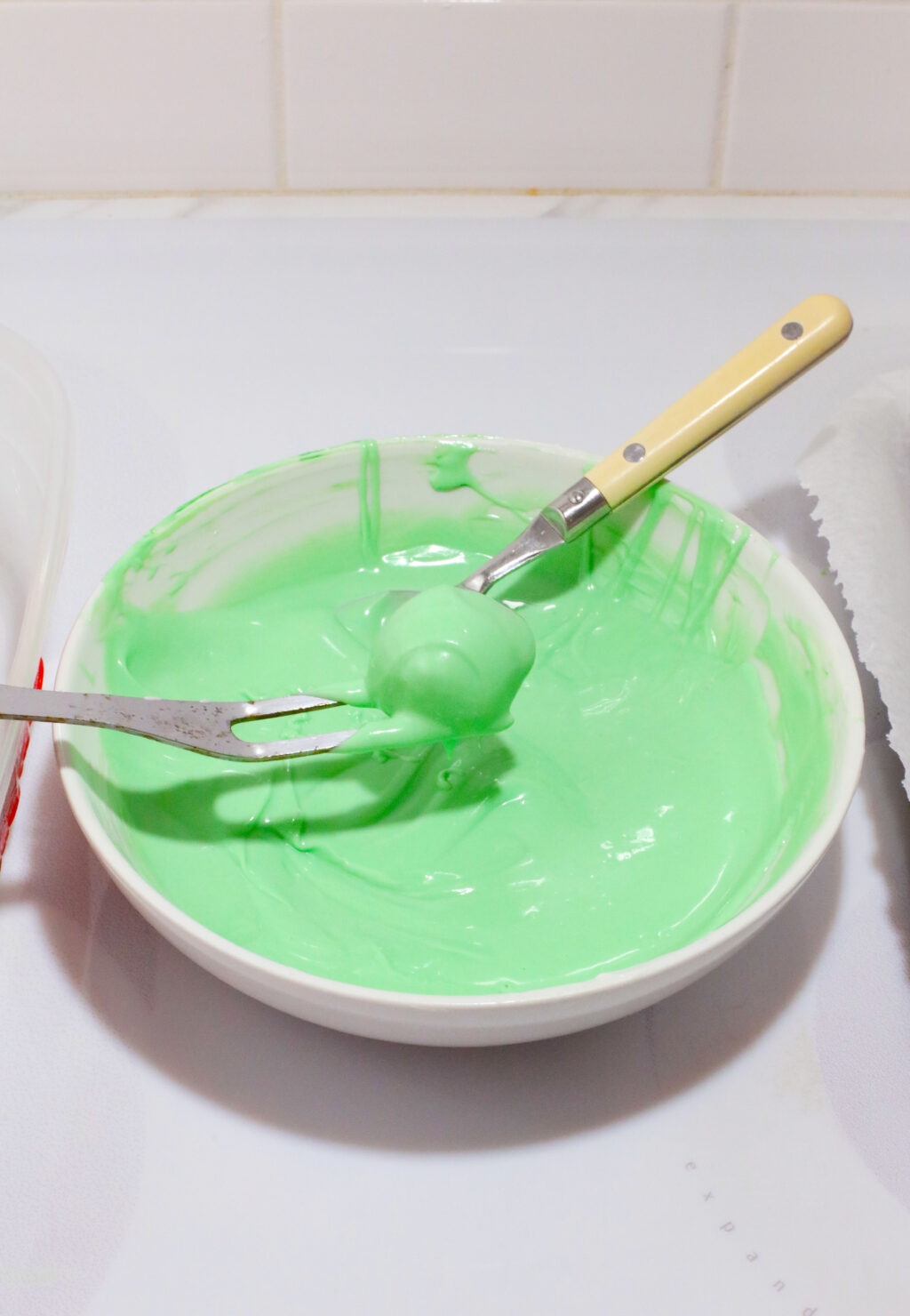 peanut butter balls being dipped into green colored chocolate