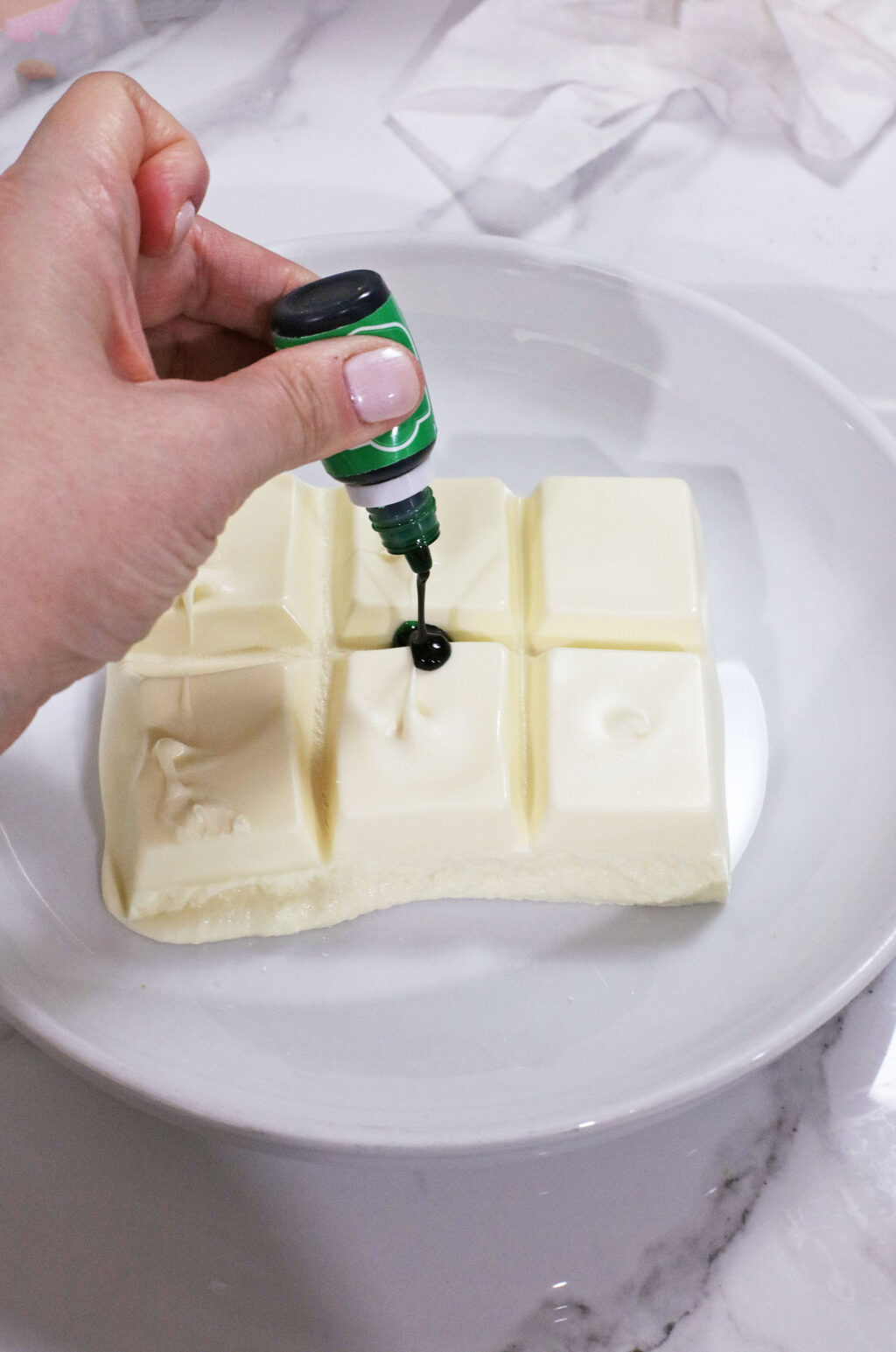 green food coloring being added to melted white almond bark