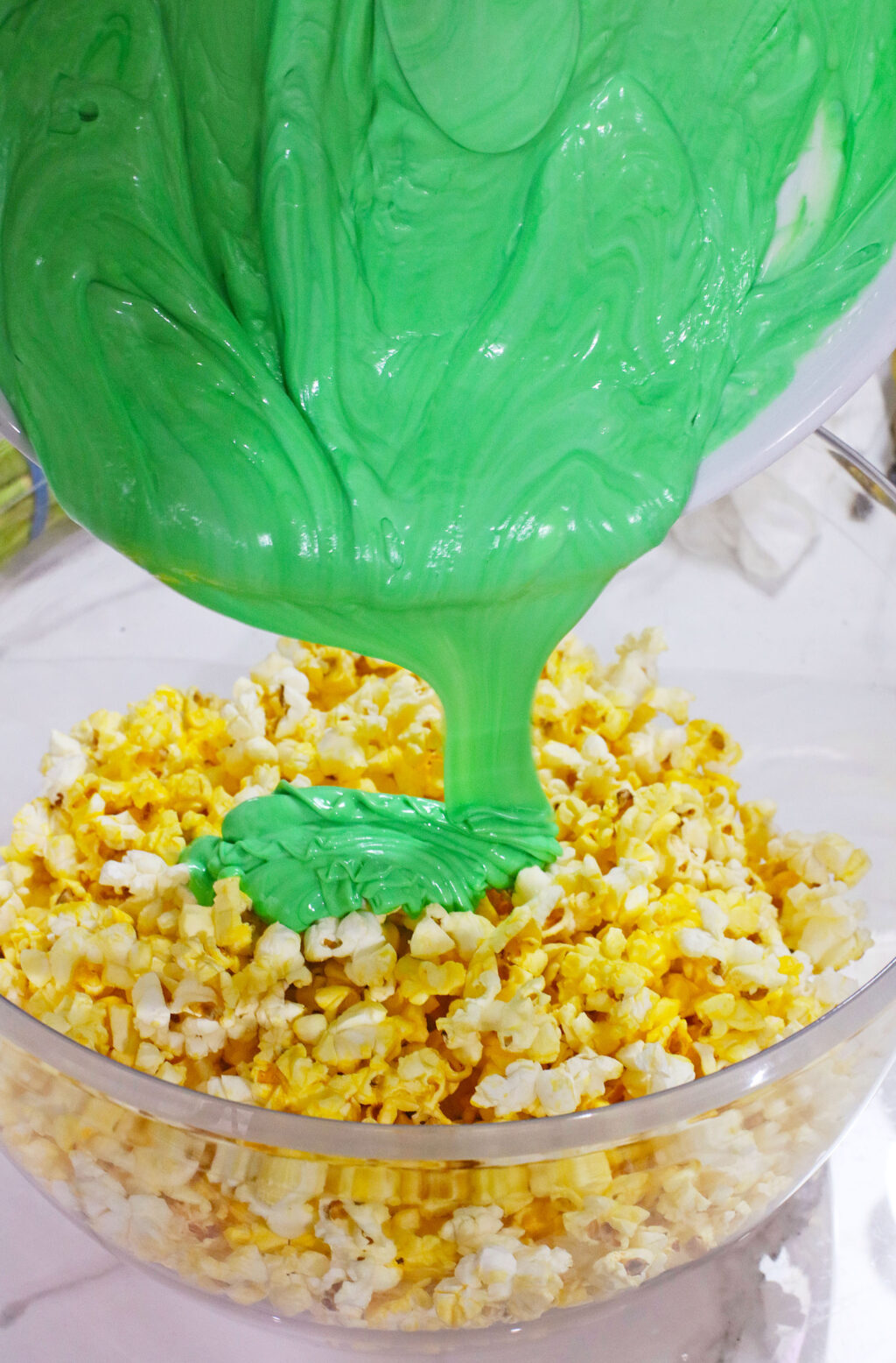green almond bark being poured over popcorn