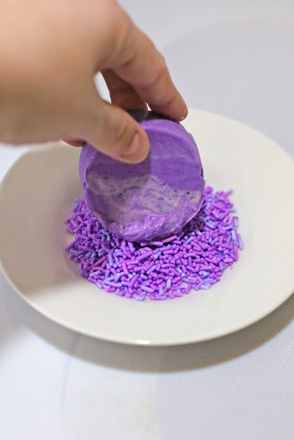 dipping purple oreo into purple sprinkles