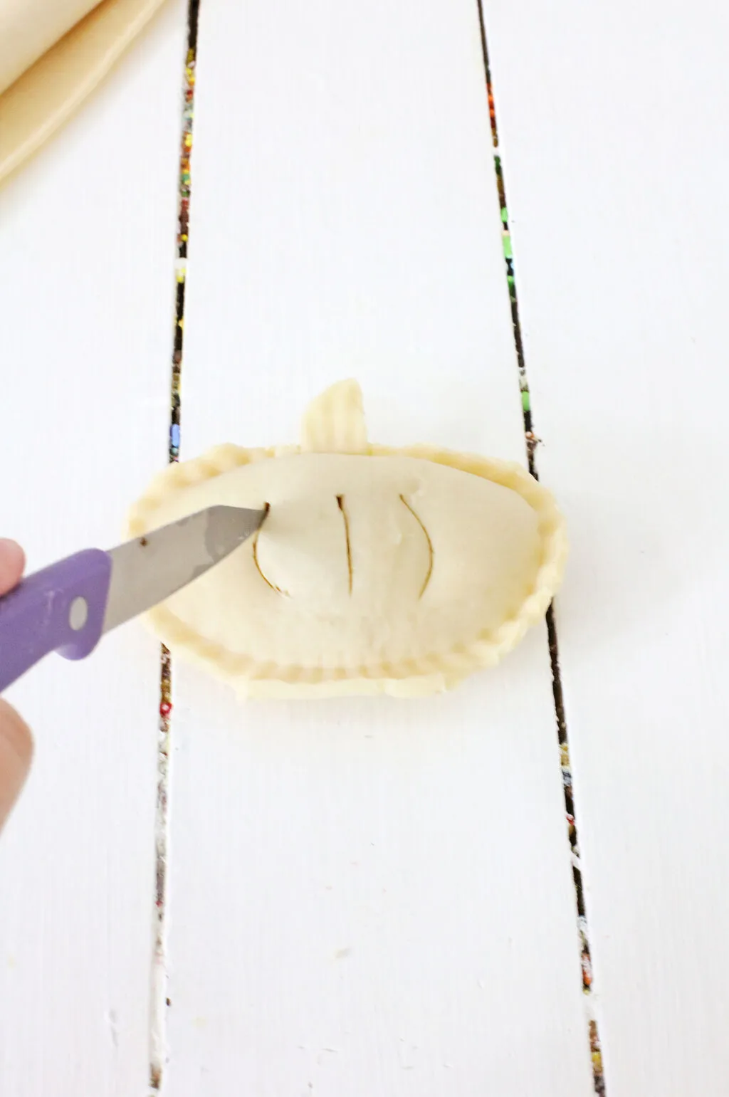 knife cutting slits into uncooked pumpkin hand pies