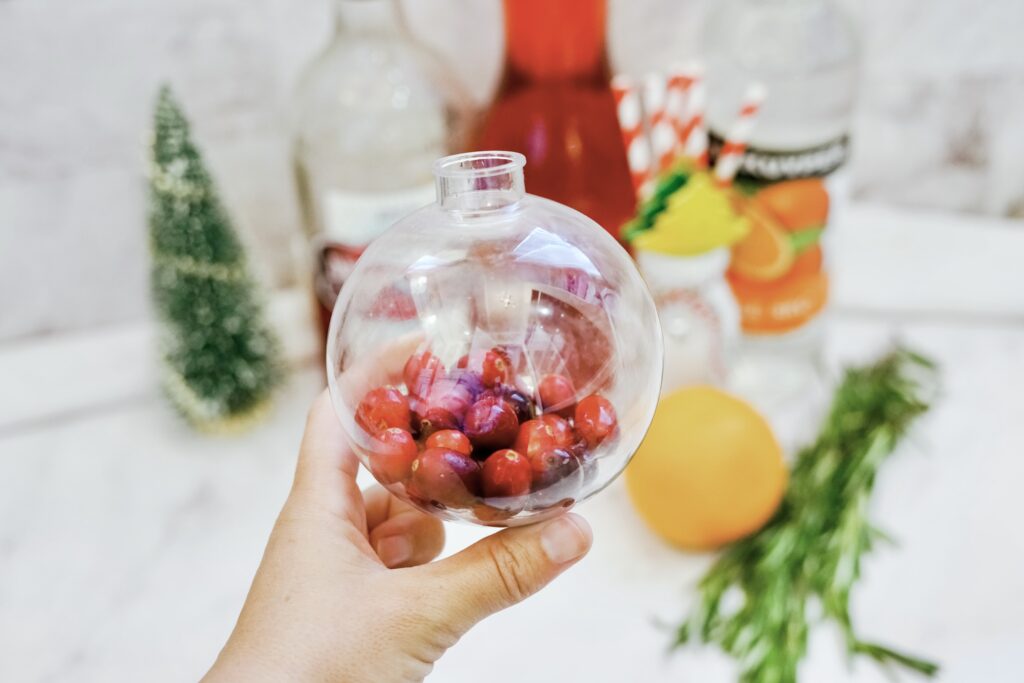 hand holding plastic ornament with fresh cranberries inside