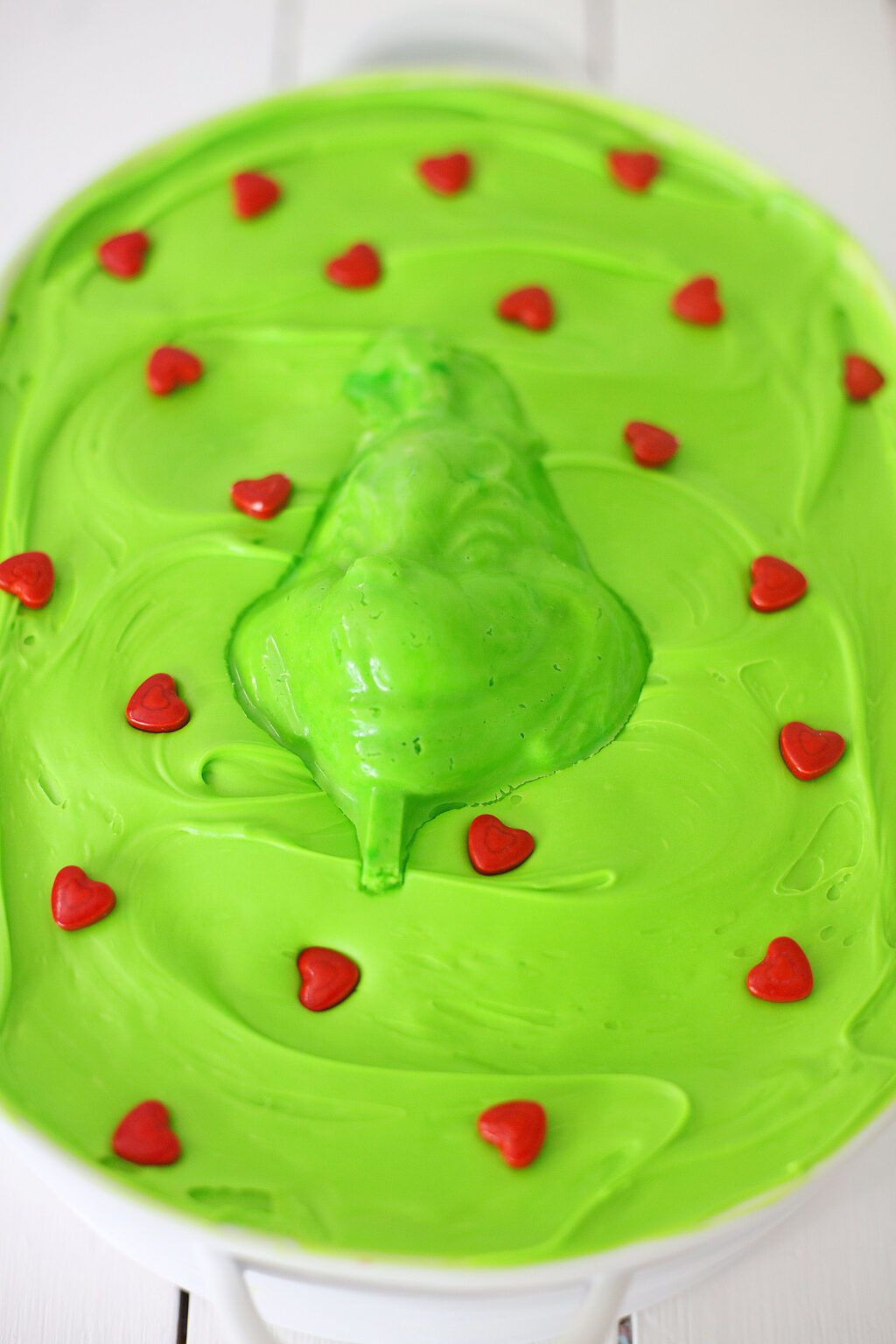grinch face on top of grinch cake with red sprinkle hearts