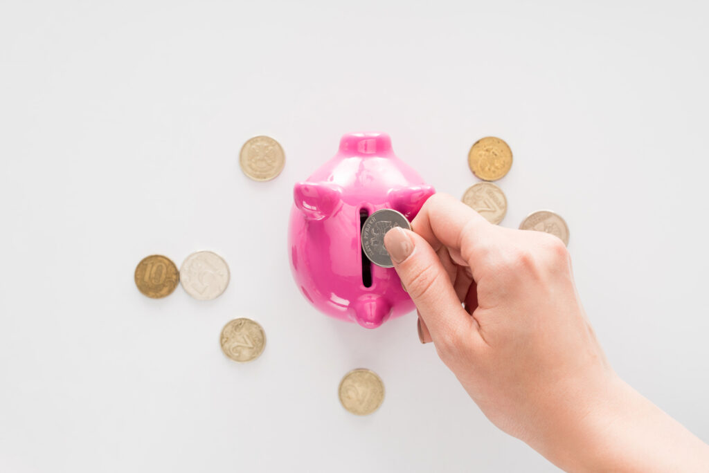 woman putting coins into pink piggybank