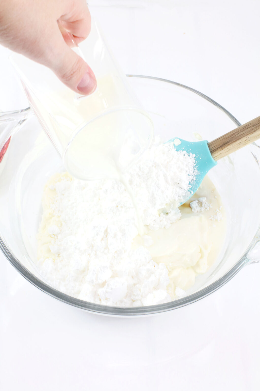 hand pouring milk into bowl with grinch dip ingredients