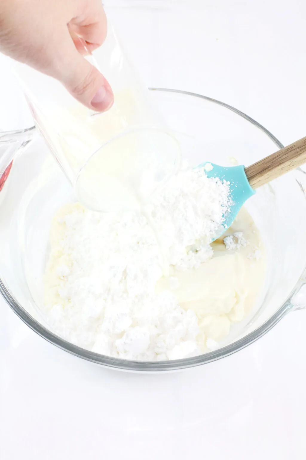 hand pouring milk into bowl with grinch dip ingredients