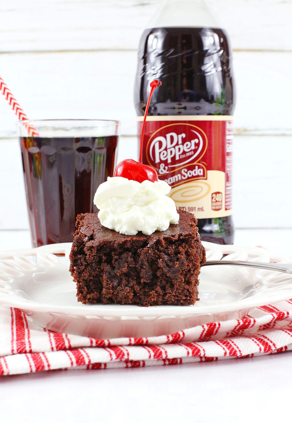 slice of dr. pepper cake on white plate with dr. pepper bottle behind it