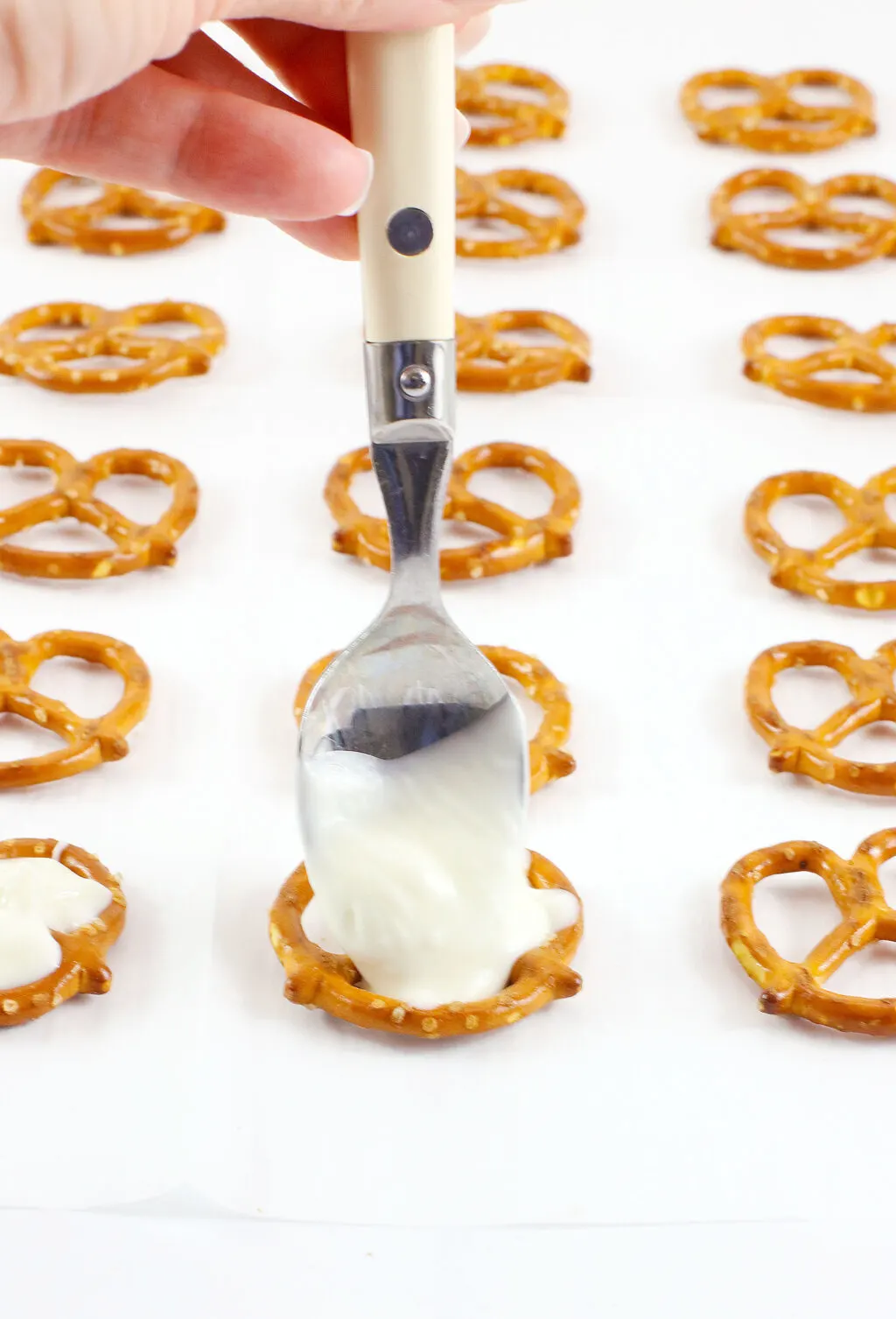 spoon with white chocolate on top of pretzel twist