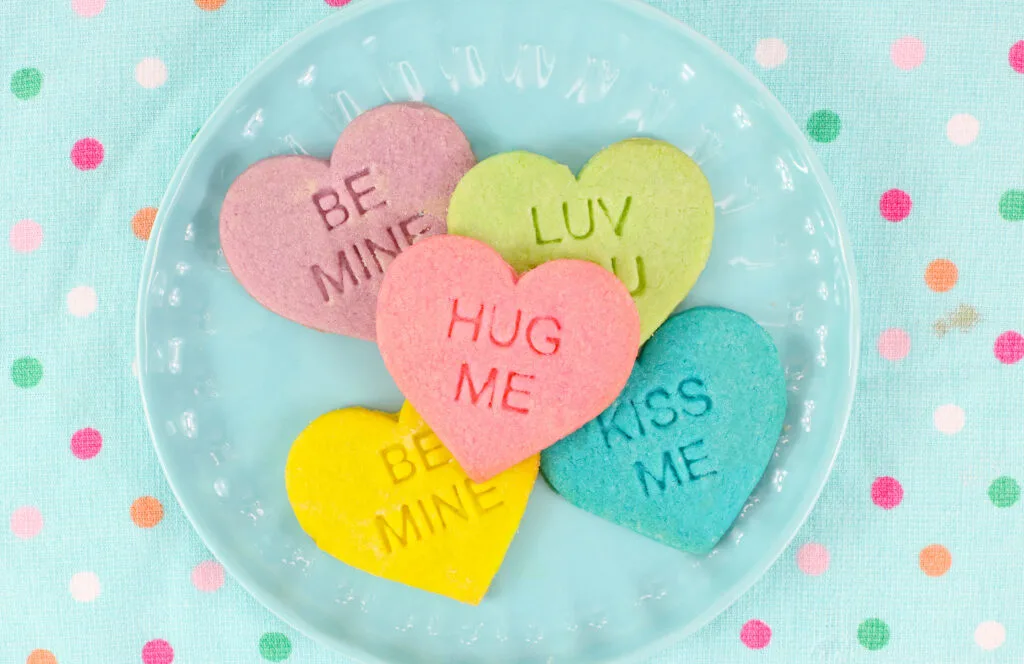 blue round plate with colorful heart conversation cookies on it