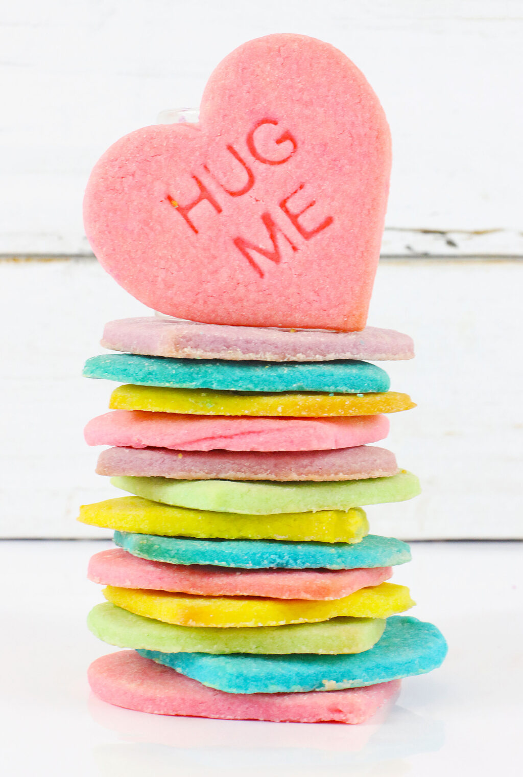 stacked conversation heart cookies on a white wood table