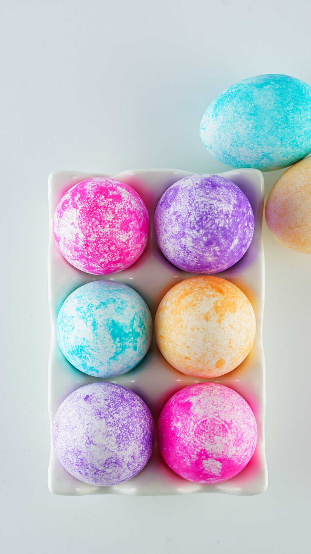 colored speckled eggs in white egg carton