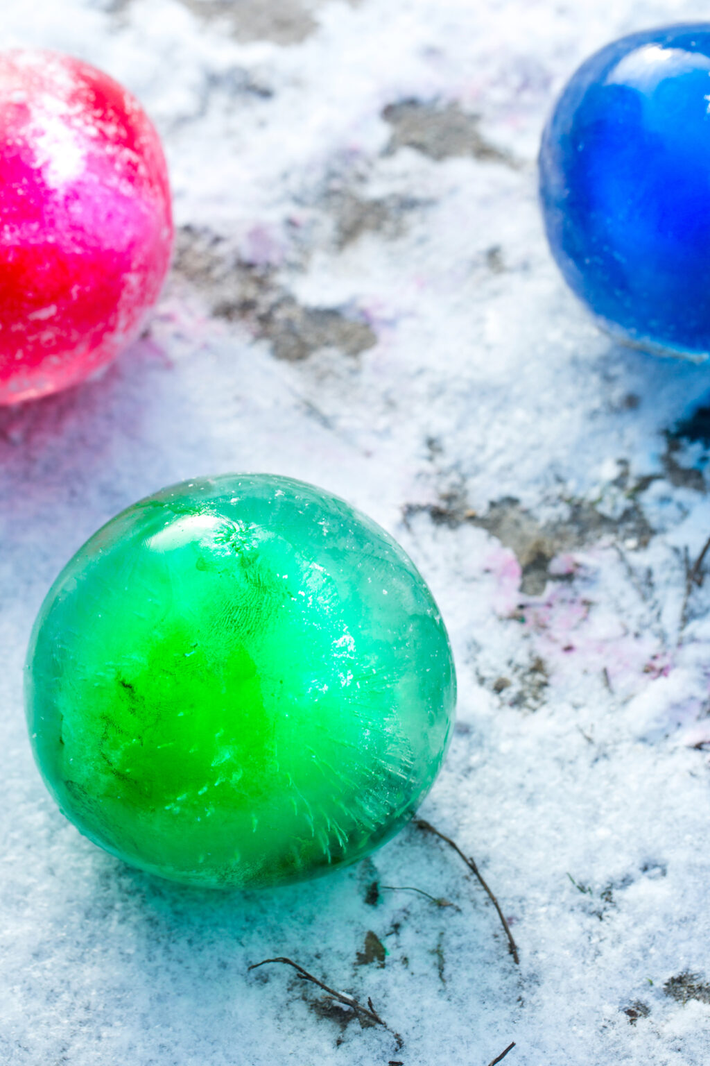 red blue and green ice marbles on snowy ground