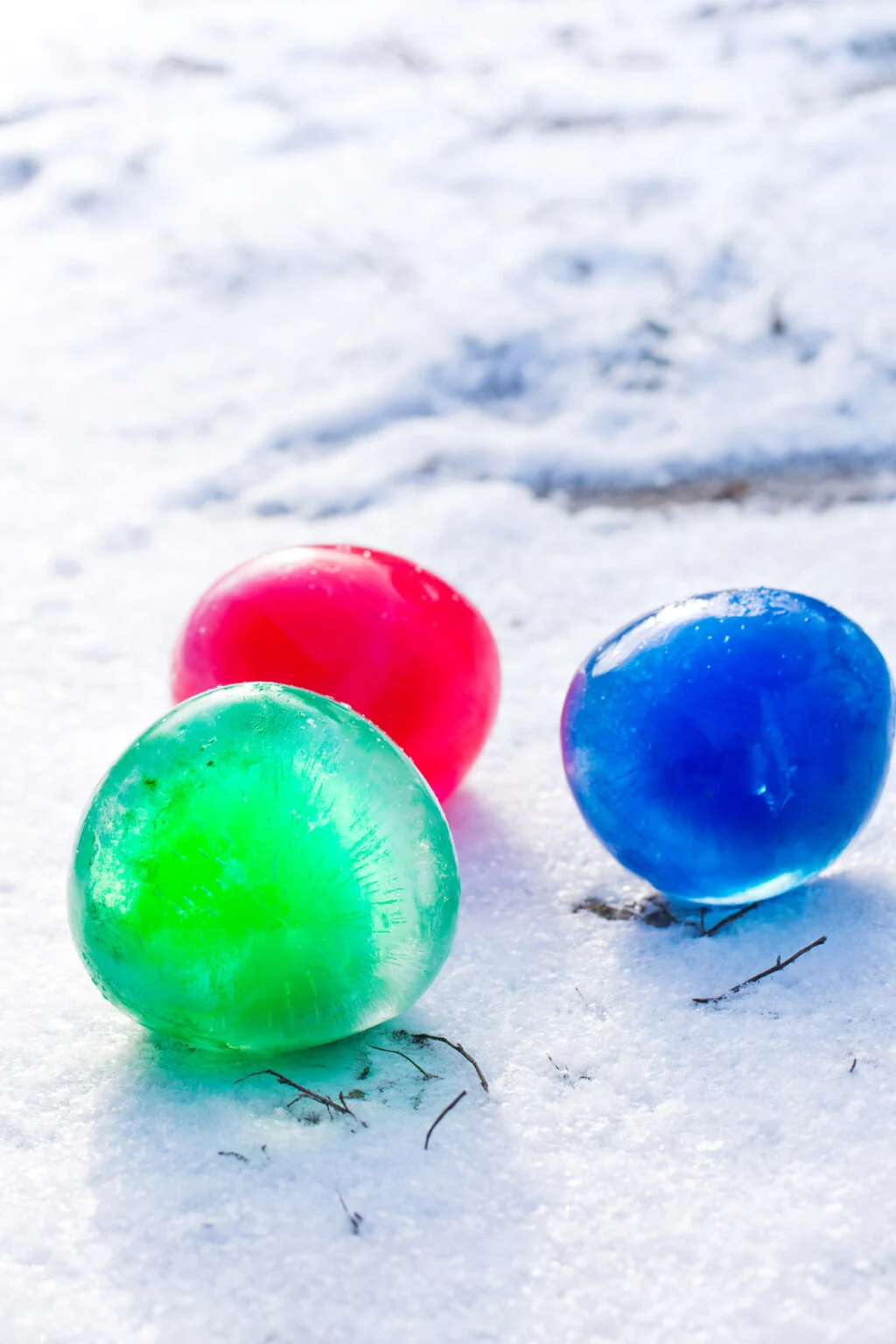 3 colored ice marbles on snowy ground