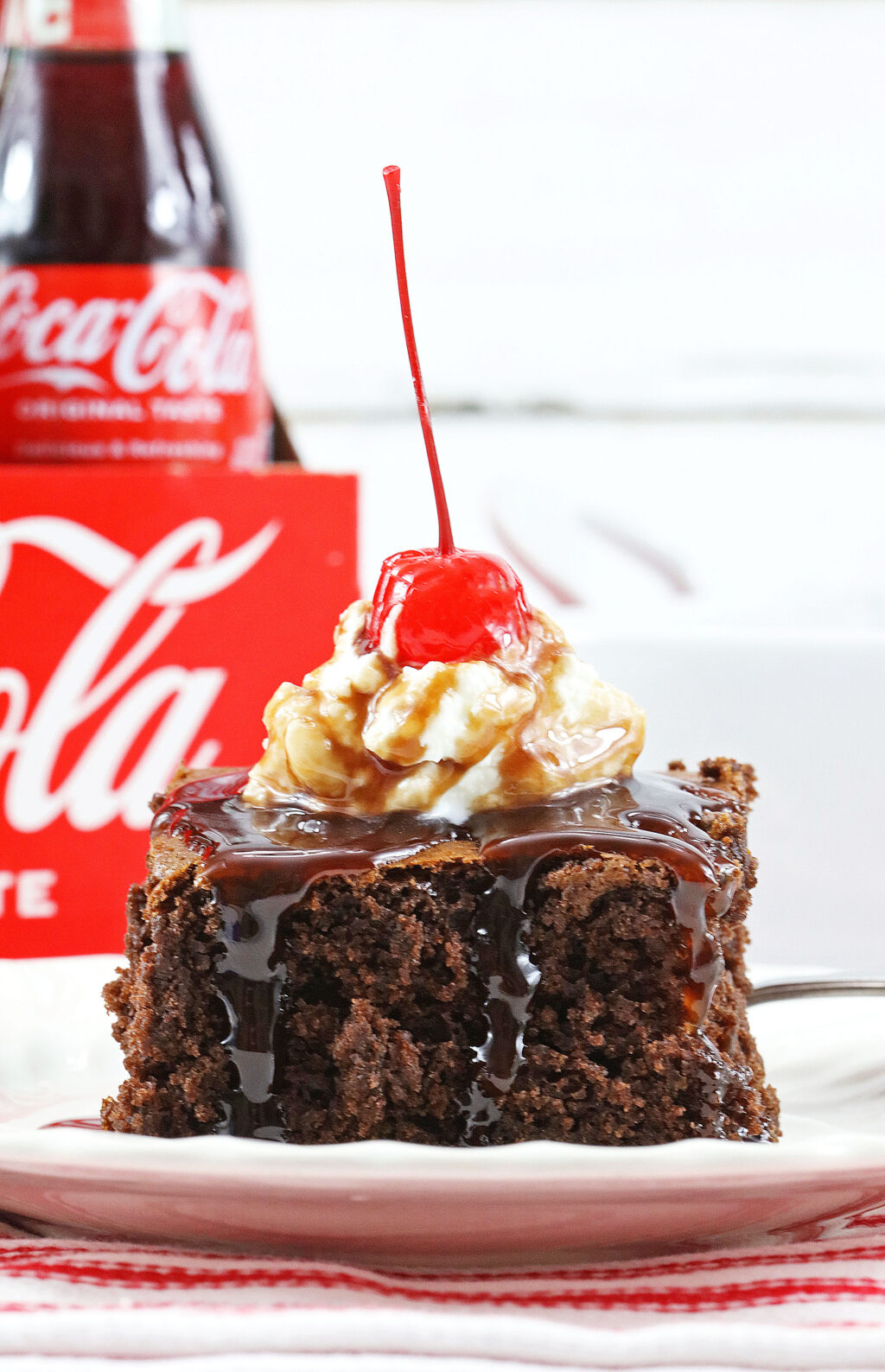 slice of 2-ingredient coke cake on a white plate with coke behind it