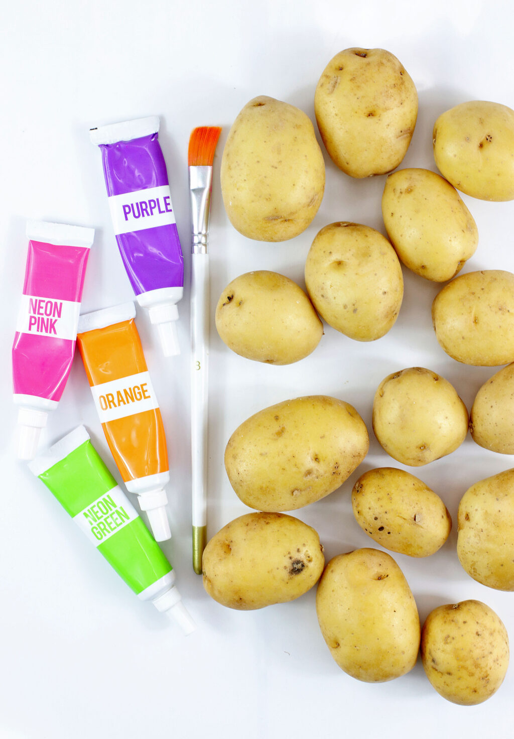 yellow potatoes with gel food coloring and a paintbrush next to it on a white table