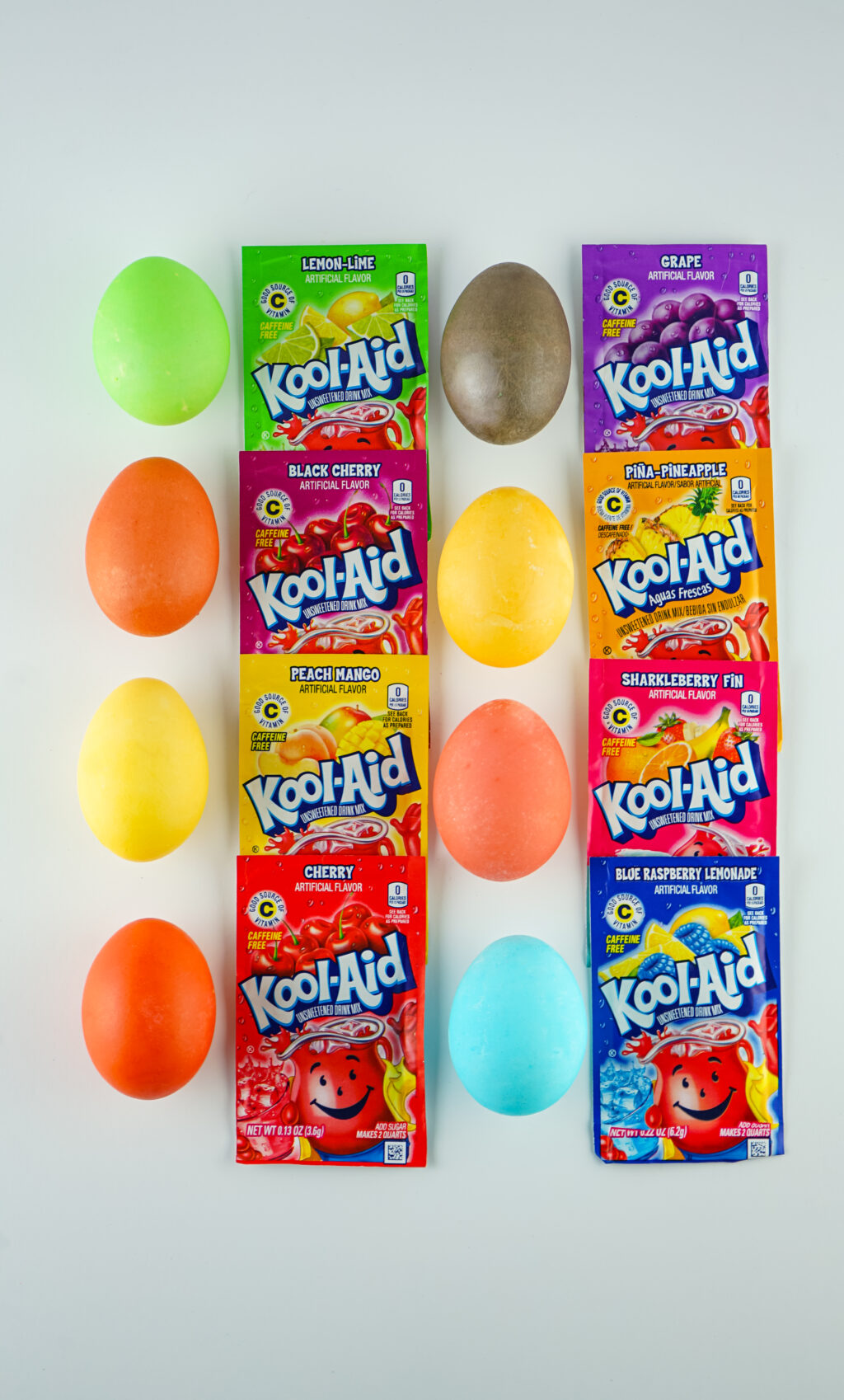 bright colored kool-aid dyed eggs with packets of kool-aid next to each colored egg