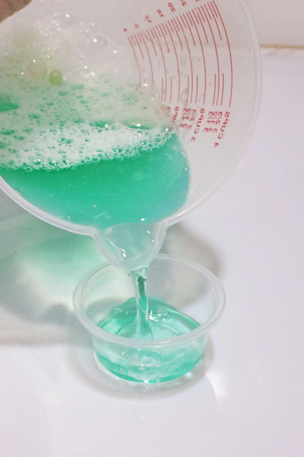 pouring blue jello shot mixture into shot glasses