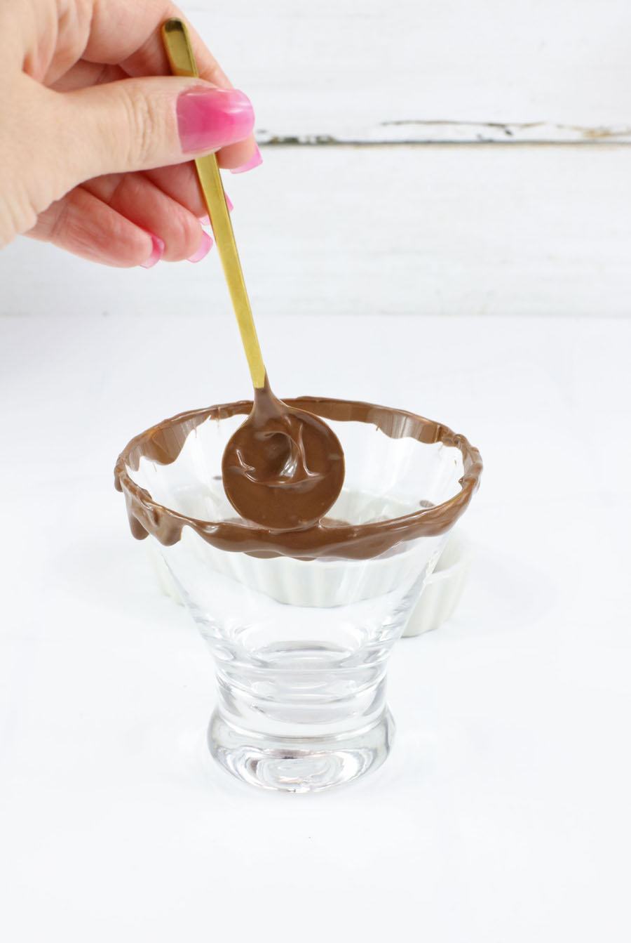 using spoon to put melted chocolate on rim of glass