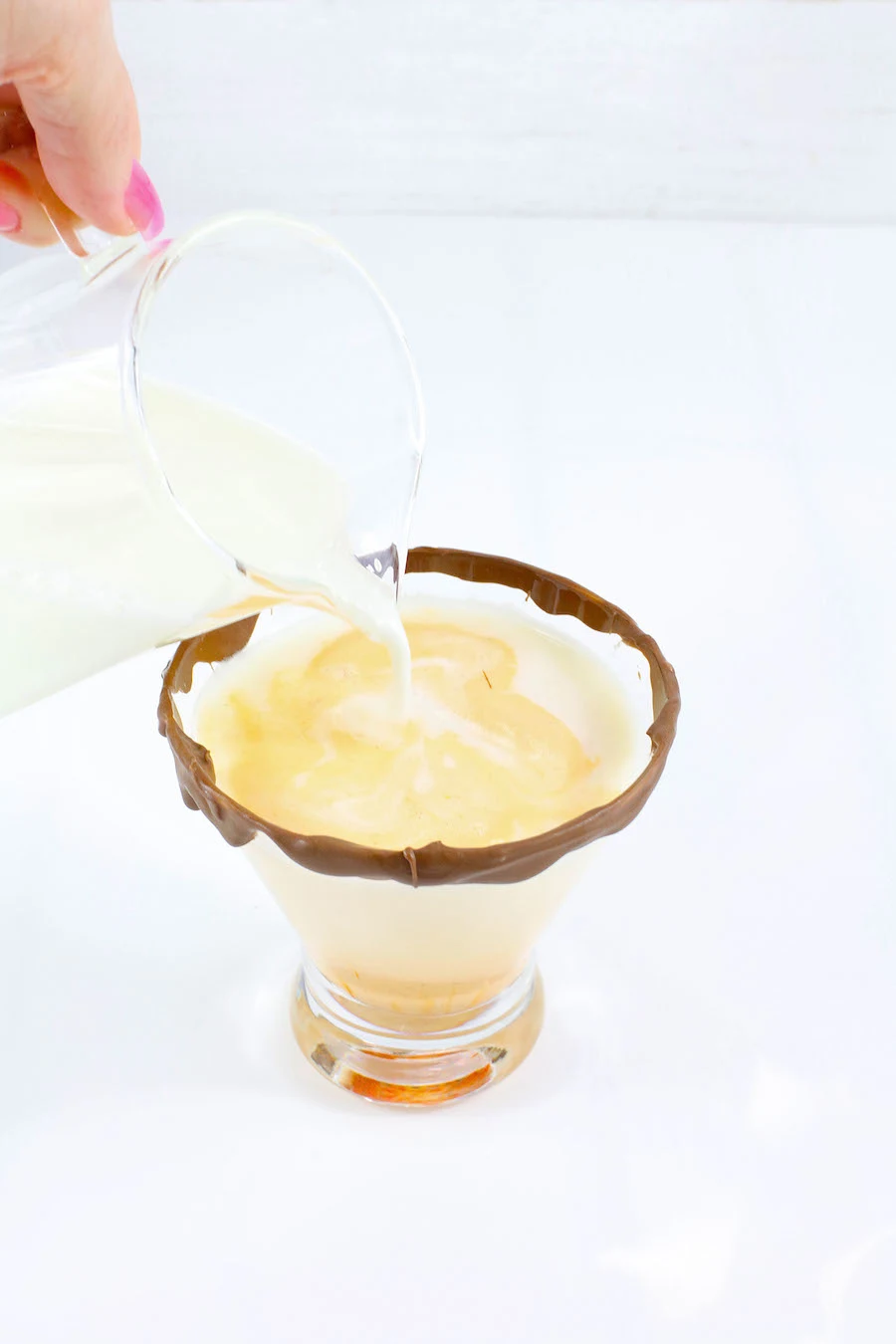 pouring in rumchata and vodka into cadbury creme egg cocktail