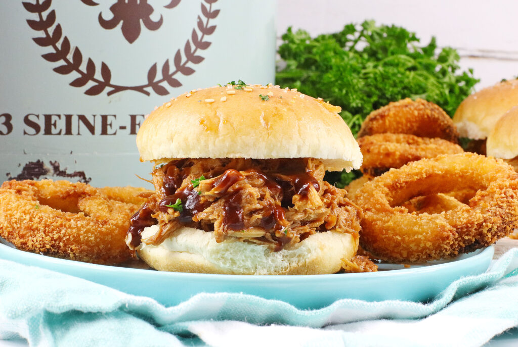 dr. pepper pulled pork with onion rings on blue plate