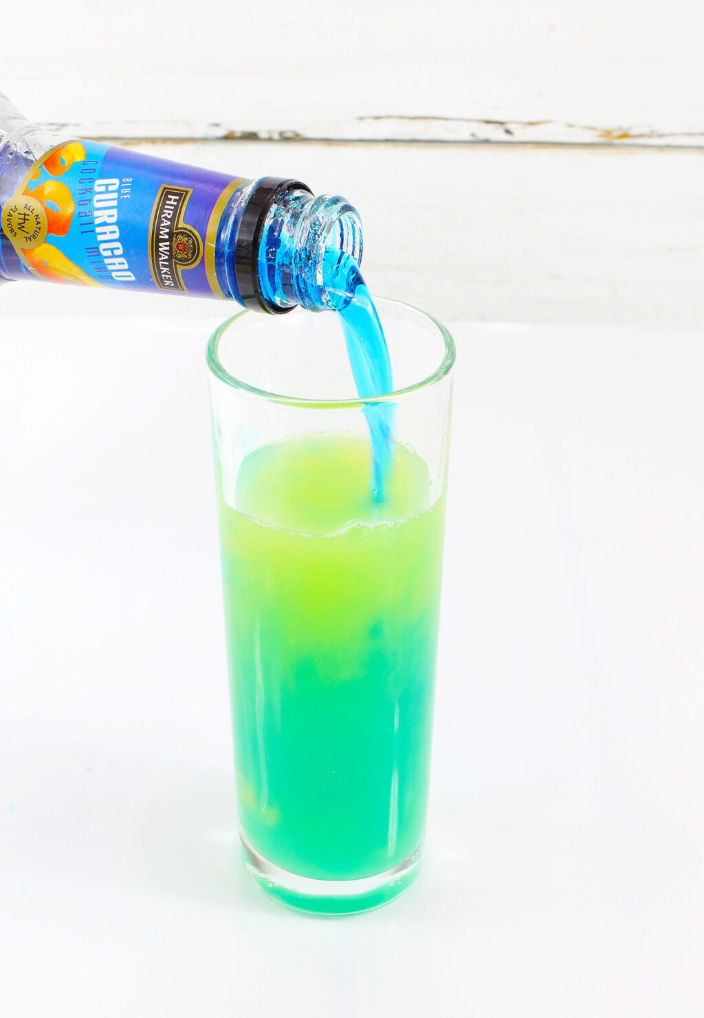 blue curacao being poured into mountain dew glass