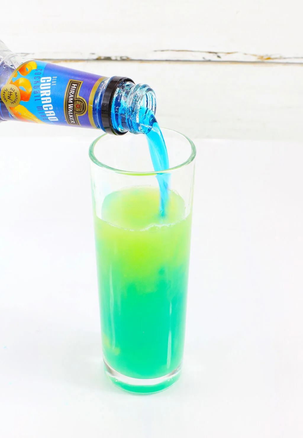 blue curacao being poured into mountain dew glass