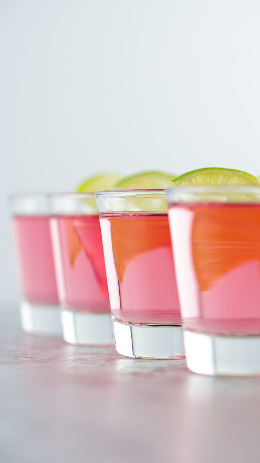 pink kamikaze shots with lime wedges on top