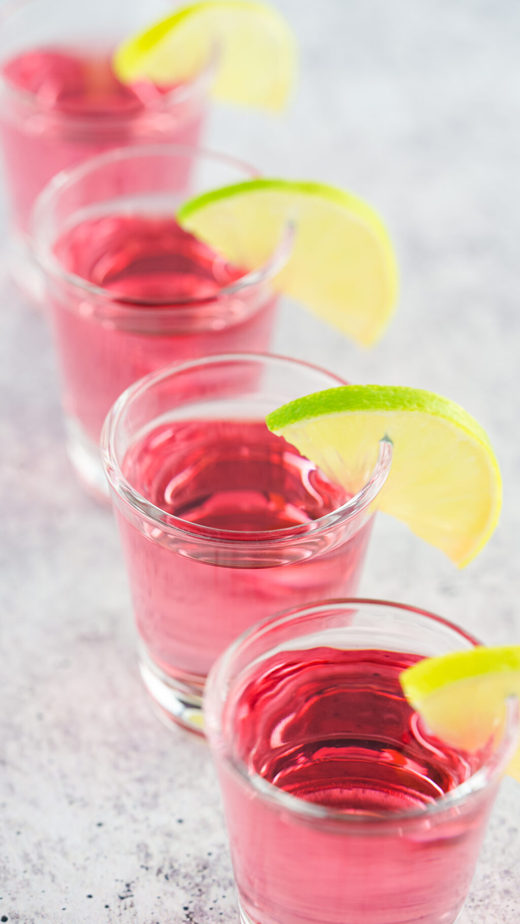 pink kamikaze shots with lime wedges