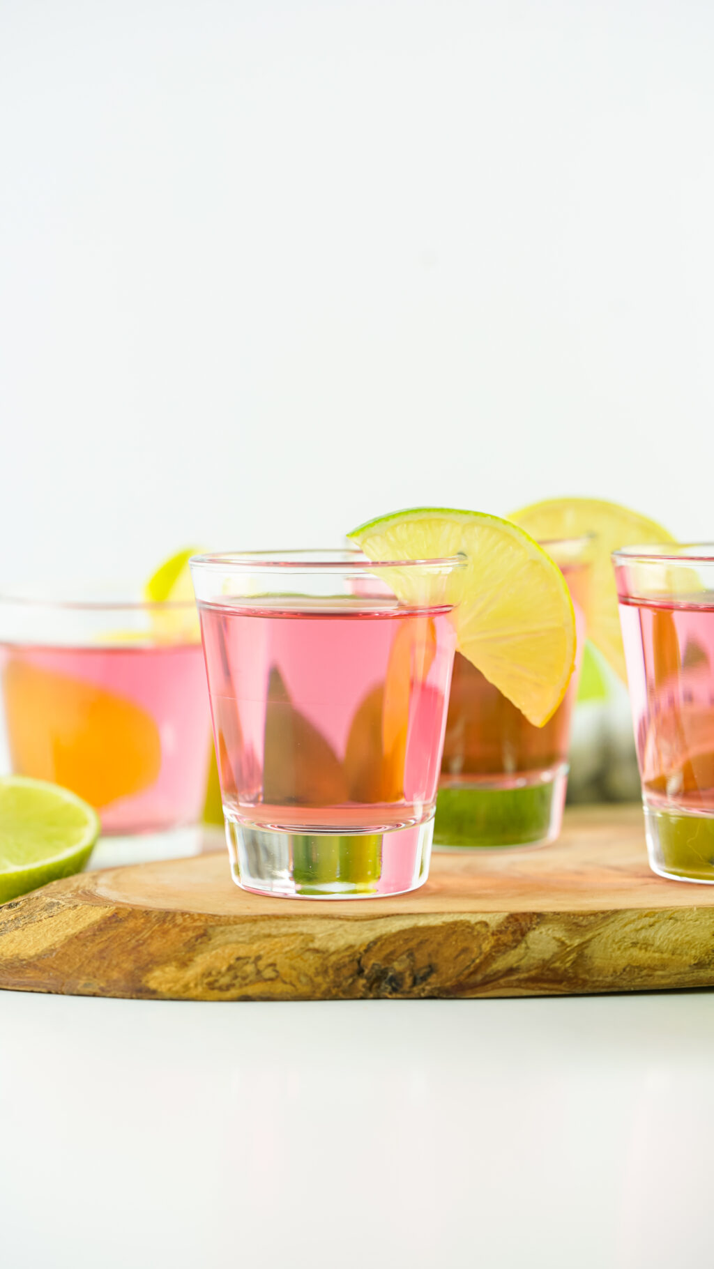 baby pink kamikaze shots with lime wedges on table