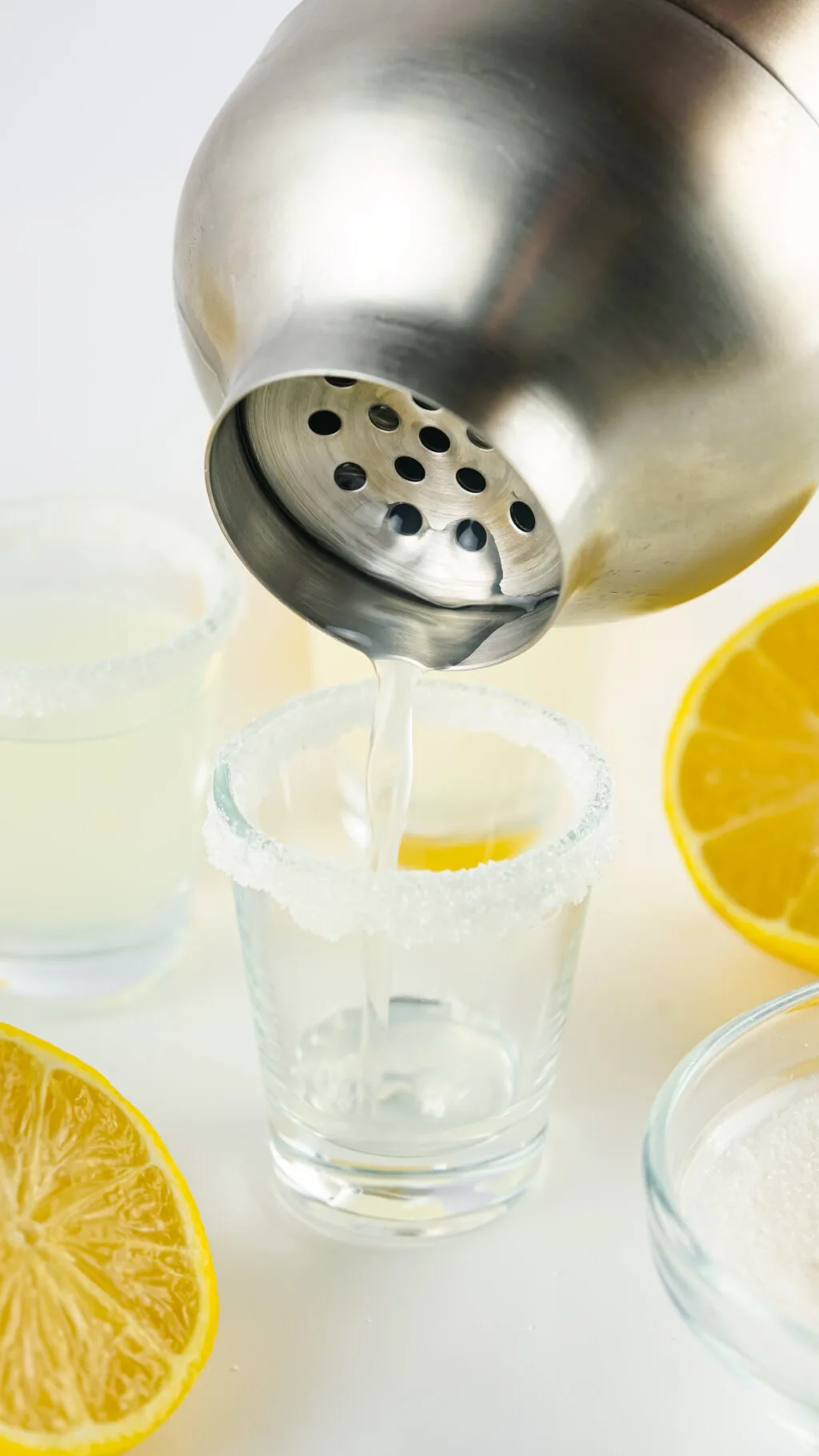 cocktail shaker pouring lemon drop shot into shot glass