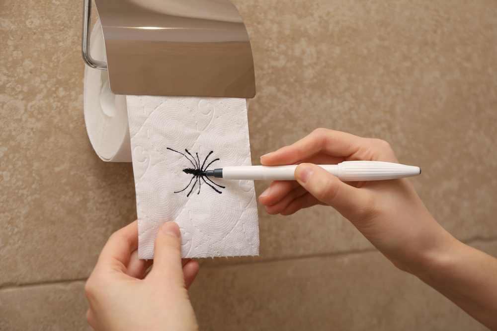 hand drawing a spider on toilet paper for fun april fools day prank