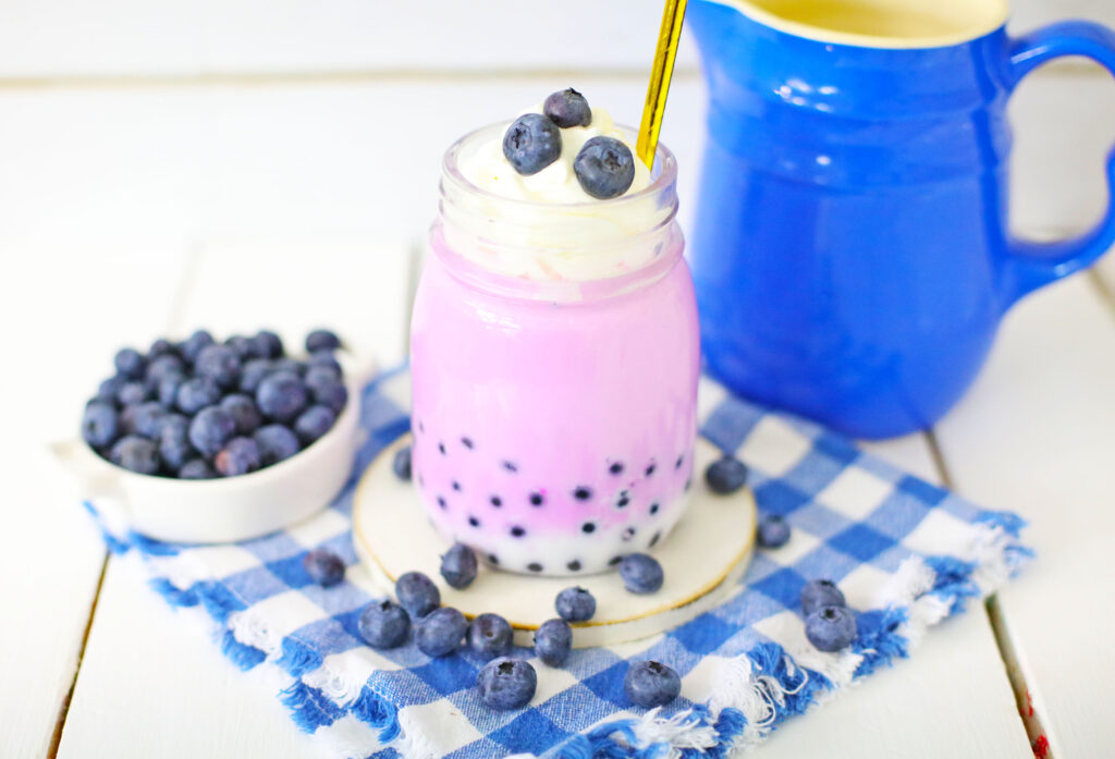 blueberry boba milk tea in glass with gold straw