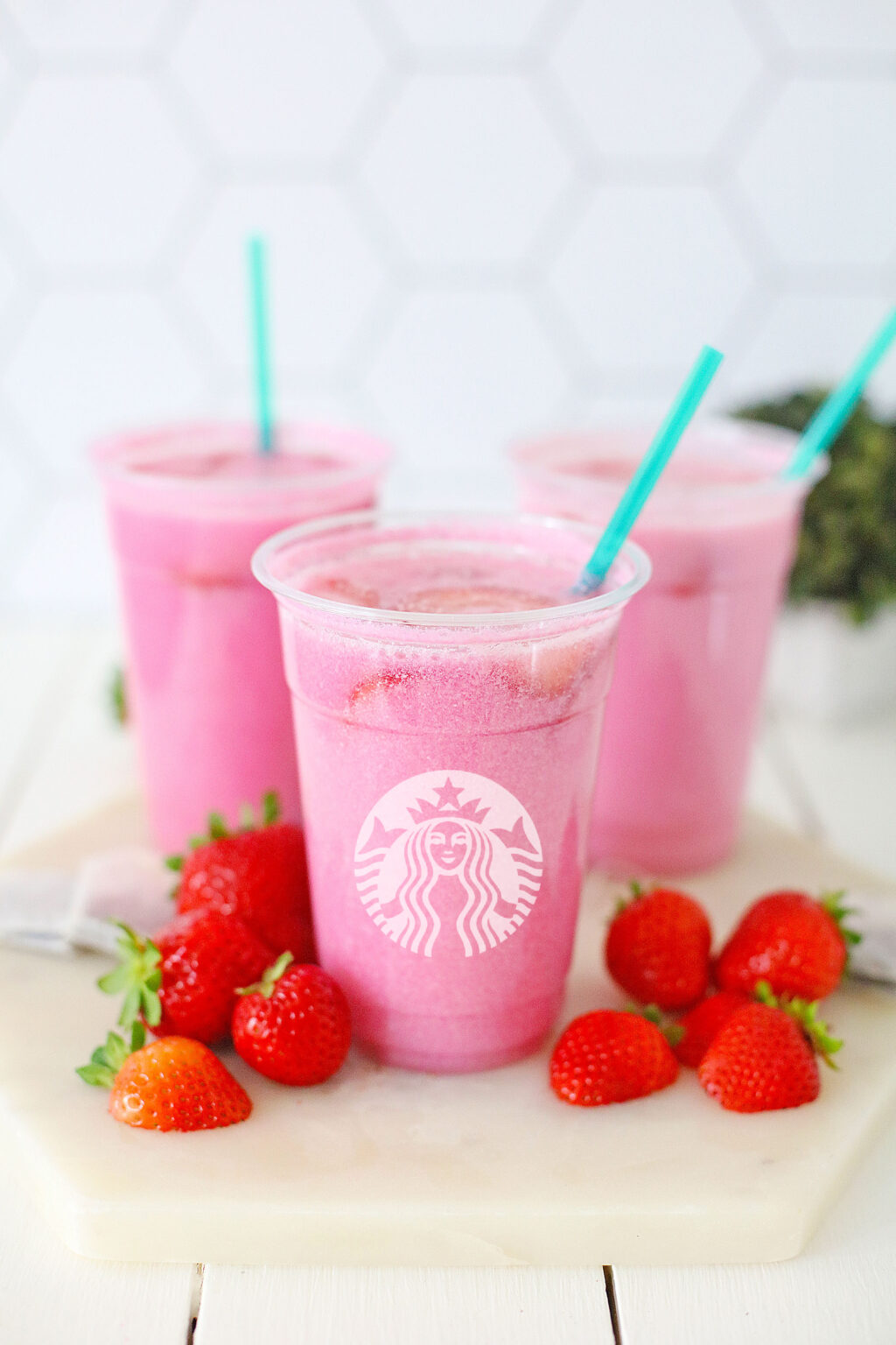 starbucks pink drink in cup with strawberries next to it