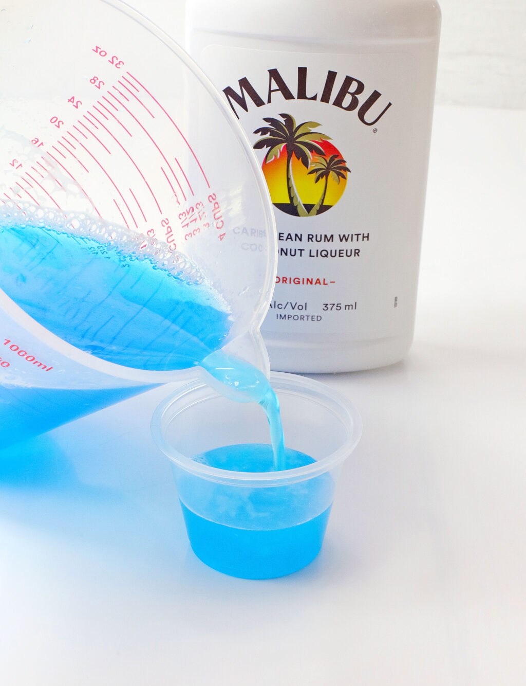 pouring blue jello into jello shot cup